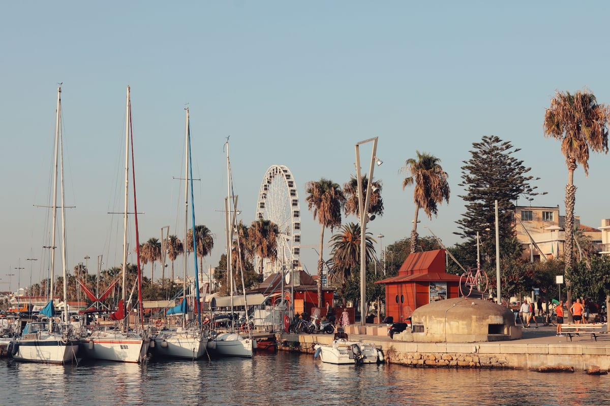 Plachetnice v prístave Alghero a promenáda s palmami