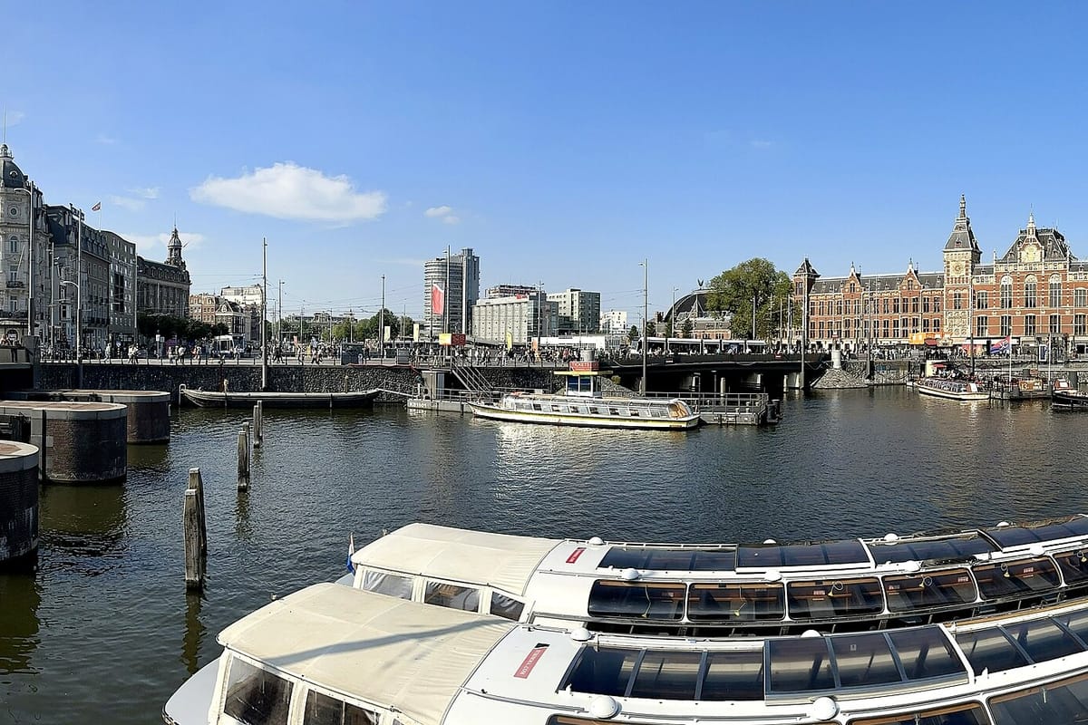 Budova stanice Amsterdam Centraal za vodou s vyhliadkovými loďami