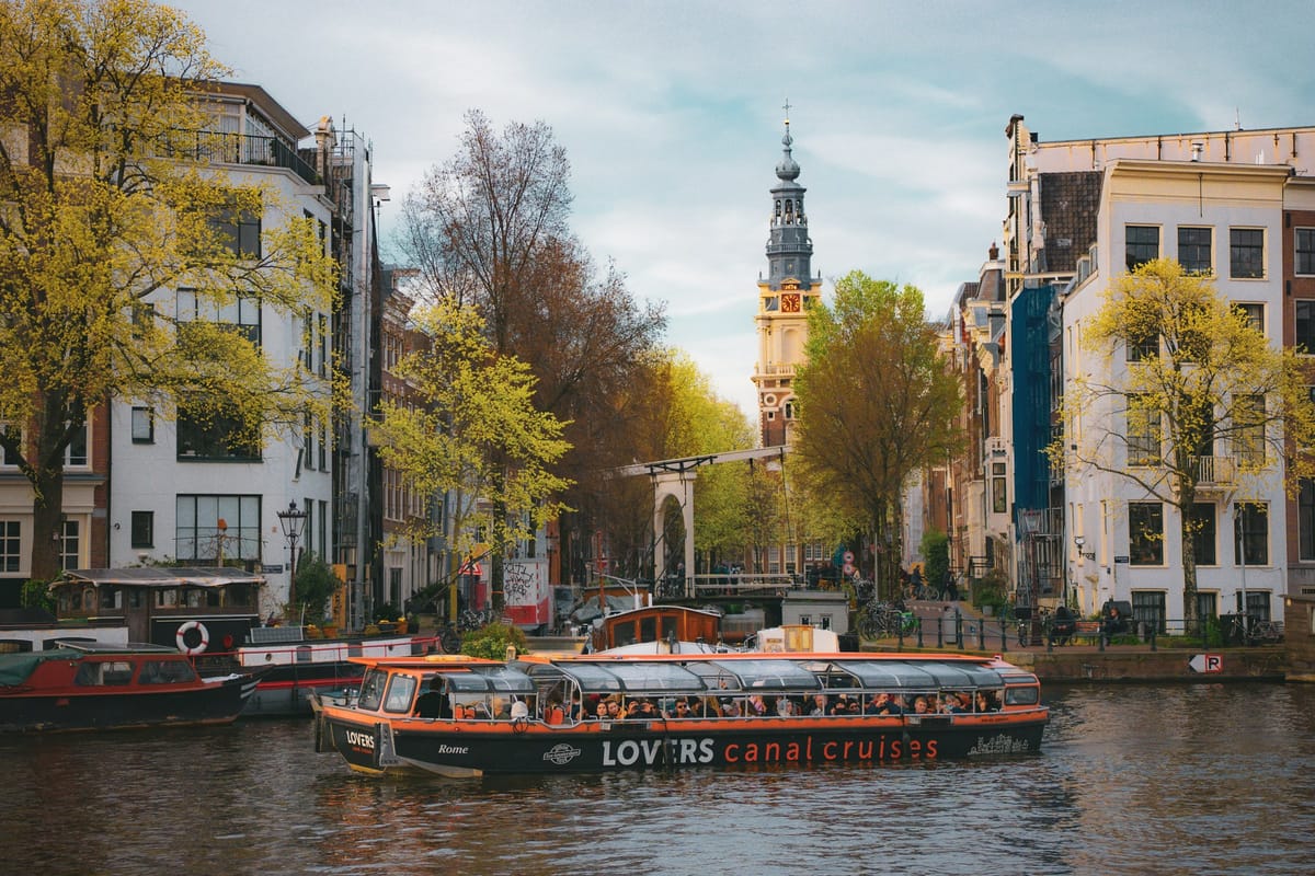 Presklená vyhliadková loď na kanáli medzi domami v Amsterdame