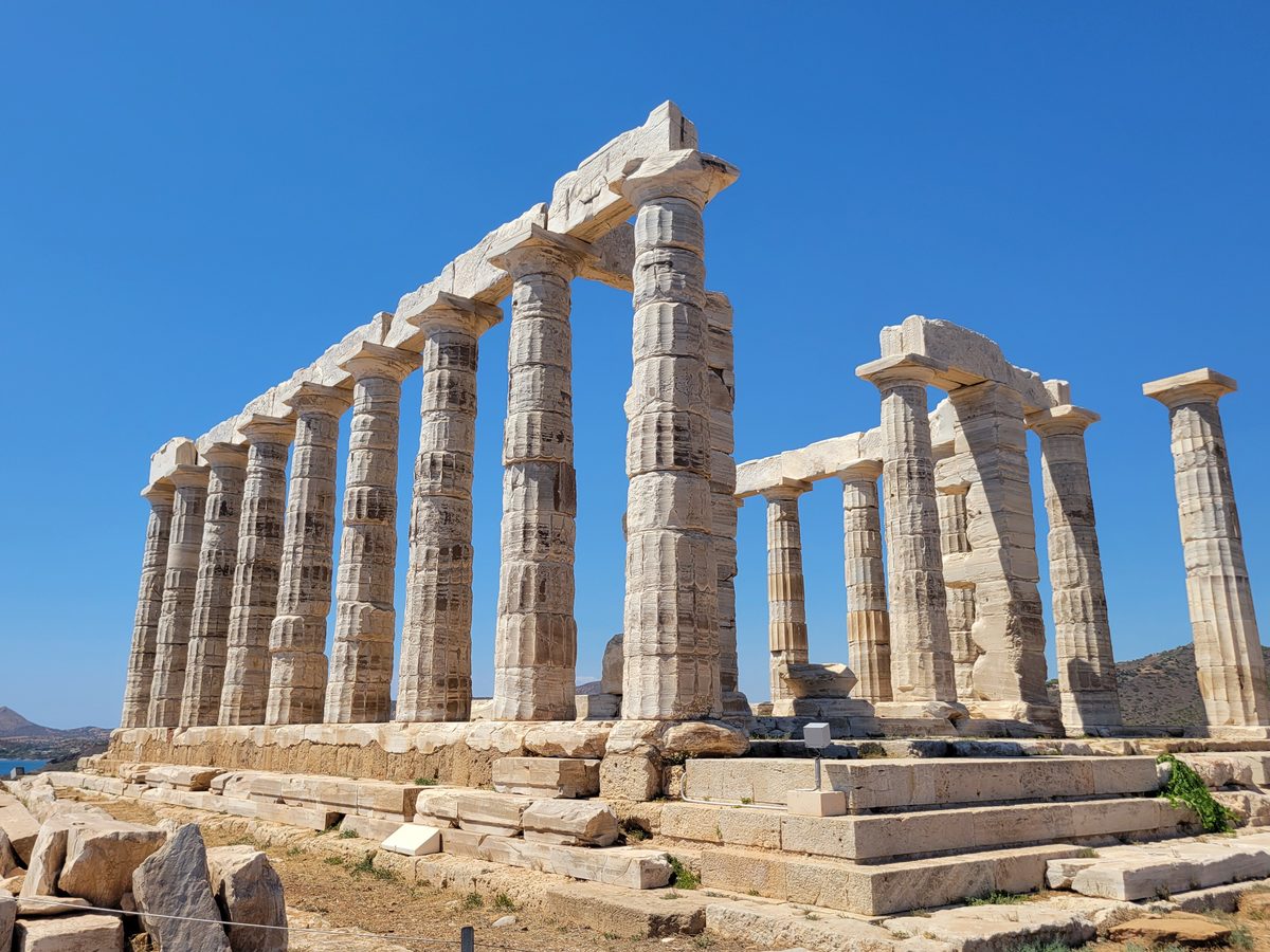 Stĺpy Poseidonovho chrámu na myse Sounion pod jasnou oblohou nad morom.