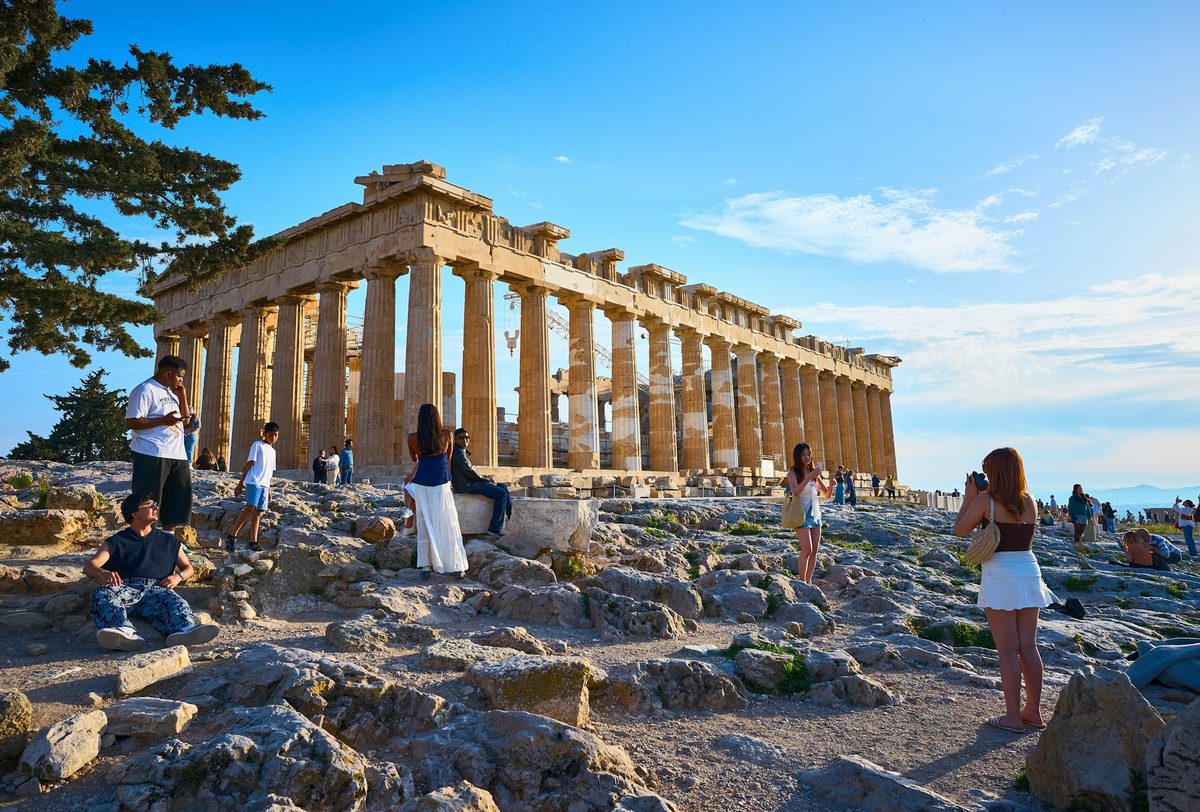 Turisti fotografujú Partenón na Akropole v Aténach za slnečného popoludnia.
