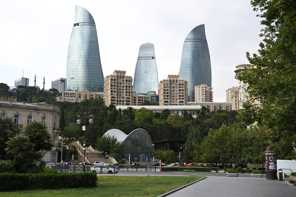 Tri sklenené veže Flame Towers nad parkom a domami v Baku