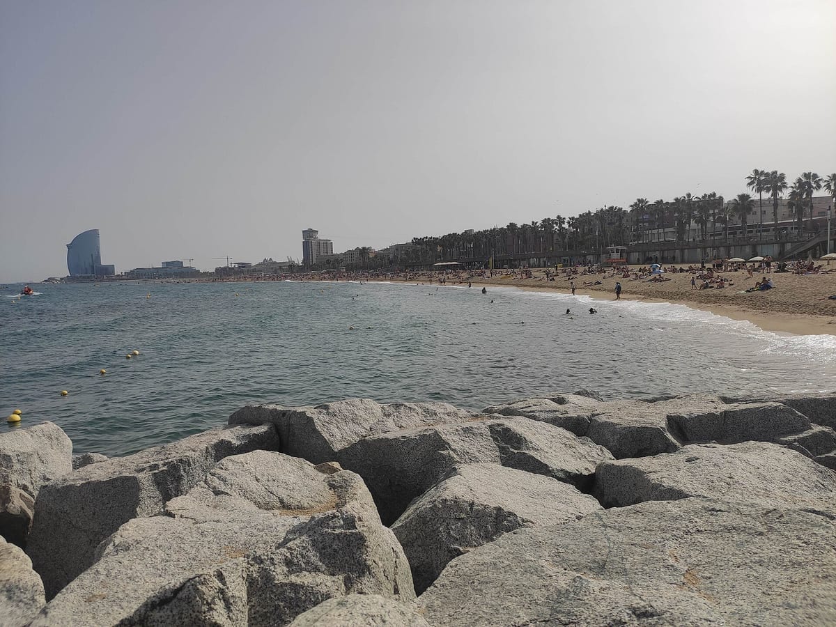 Pláž Barceloneta v lete, v pozadí hotel W Barcelona