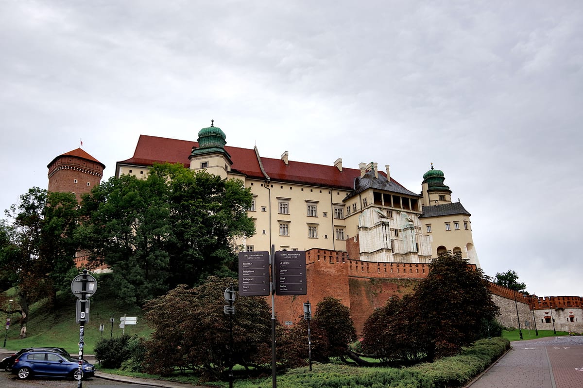 Hradby a zámok Wawel na kopci nad stromami, pohľad zdola od cesty pod hradom