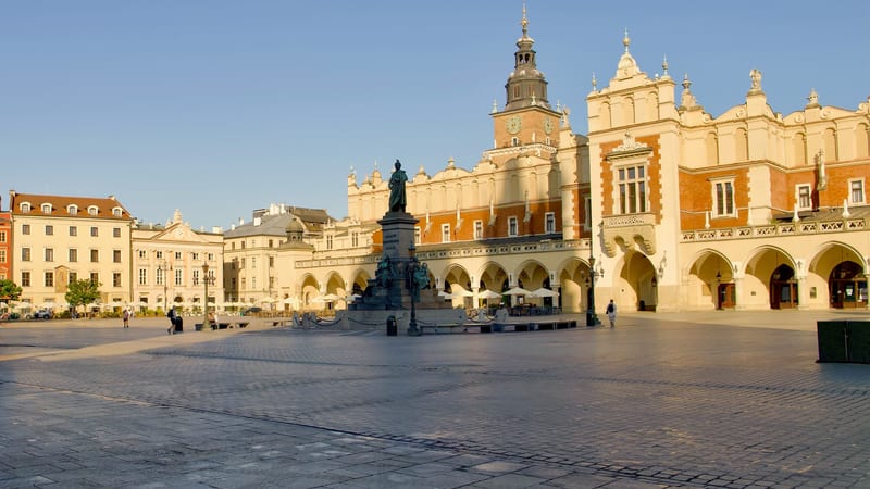 Prázdny Rynek Główny v Krakove skoro ráno so Sukiennicami, radničnou vežou a pomníkom Mickiewicza