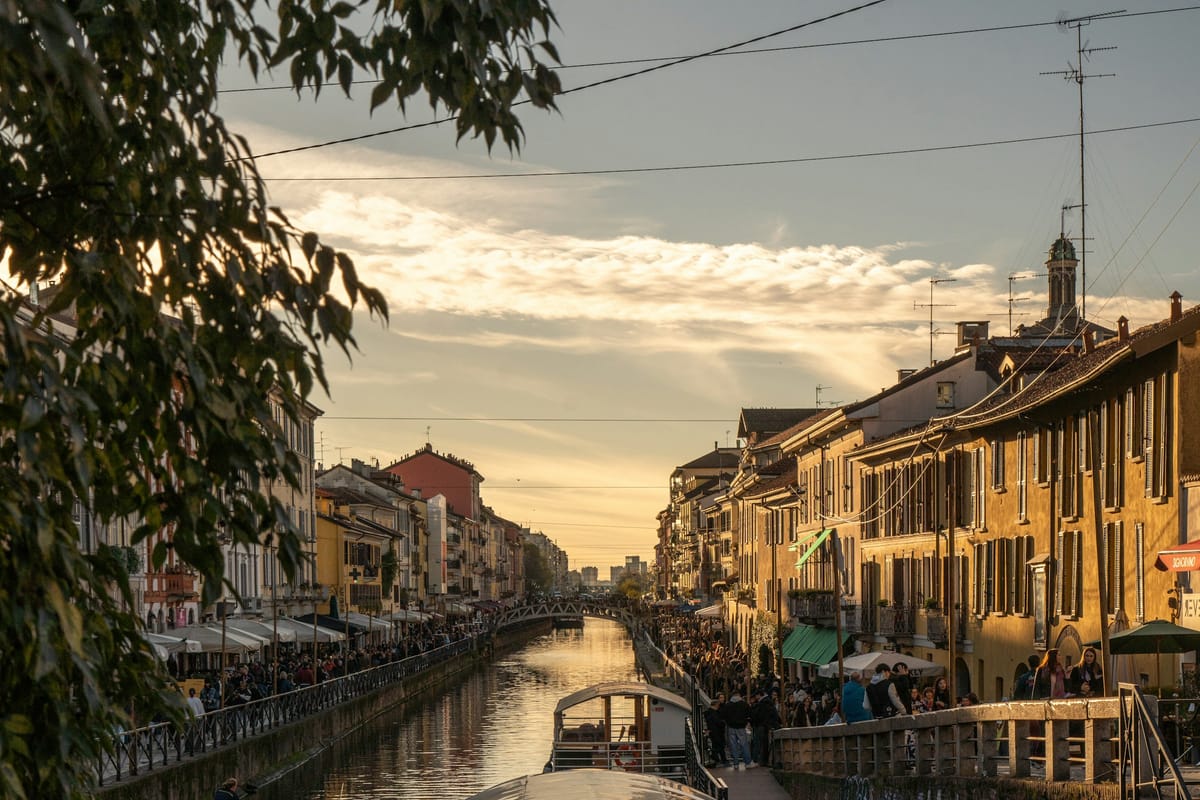 Kanál Naviglio Grande pri západe slnka s loďkami a podnikmi na nábreží
