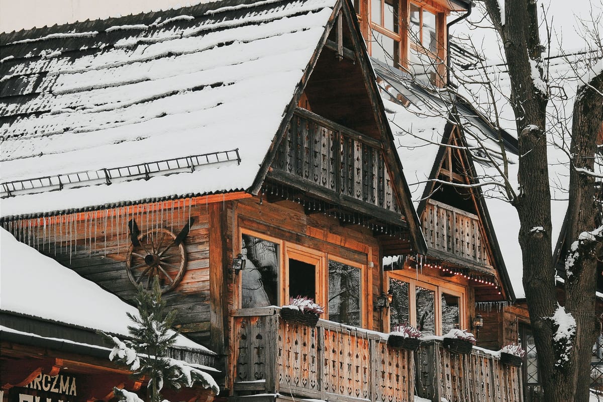 Drevená vila so zasneženou strechou a vyrezávaným balkónom v Zakopanom