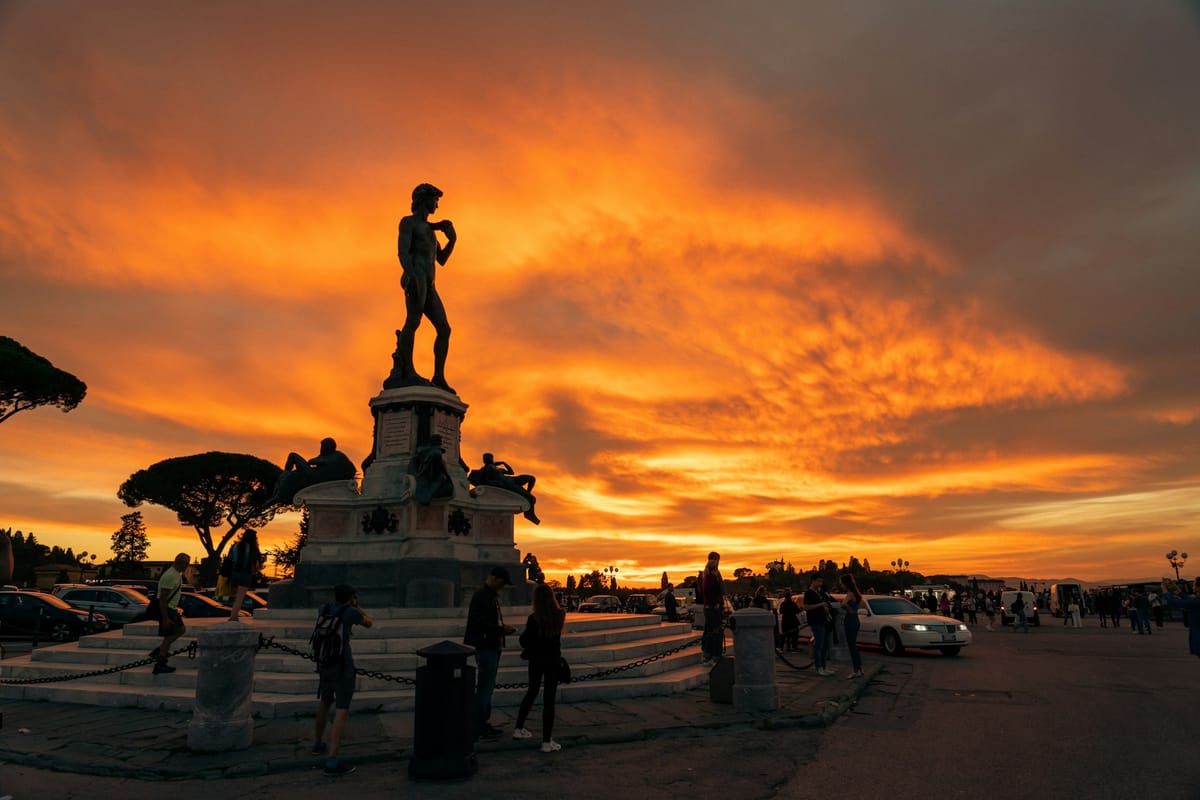 Ľudia pri kópii Dávida na Piazzale Michelangelo počas oranžového západu slnka