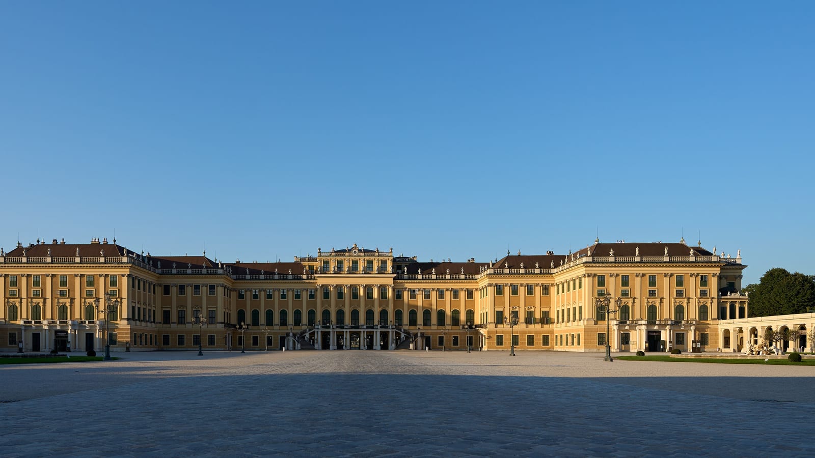 Žltá fasáda zámku Schönbrunn vo Viedni s veľkým nádvorím v rannom svetle