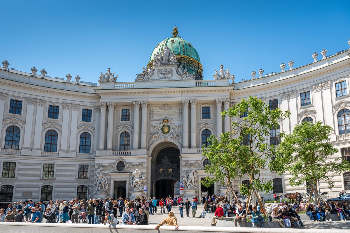 Michaelerplatz s kupolou a hlavným vstupom do Hofburgu, pred ním ľudia na námestí