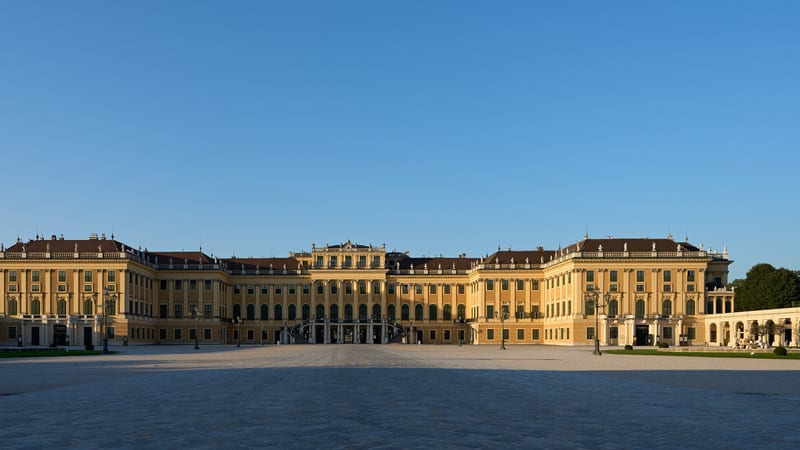 Žltá fasáda zámku Schönbrunn vo Viedni s veľkým nádvorím v rannom svetle