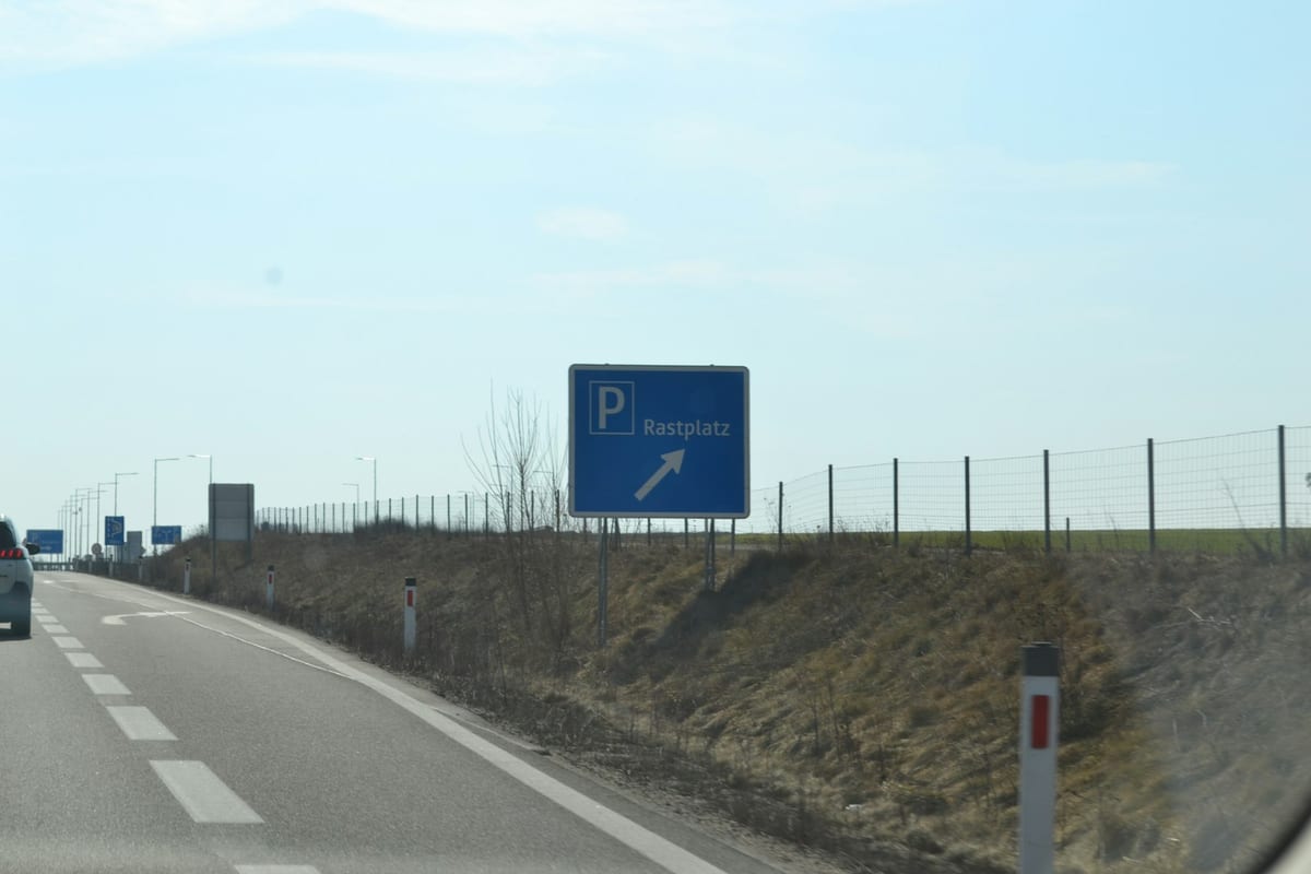 Modrá tabuľa Rastplatz so šípkou k odpočívadlu pri rakúskej diaľnici