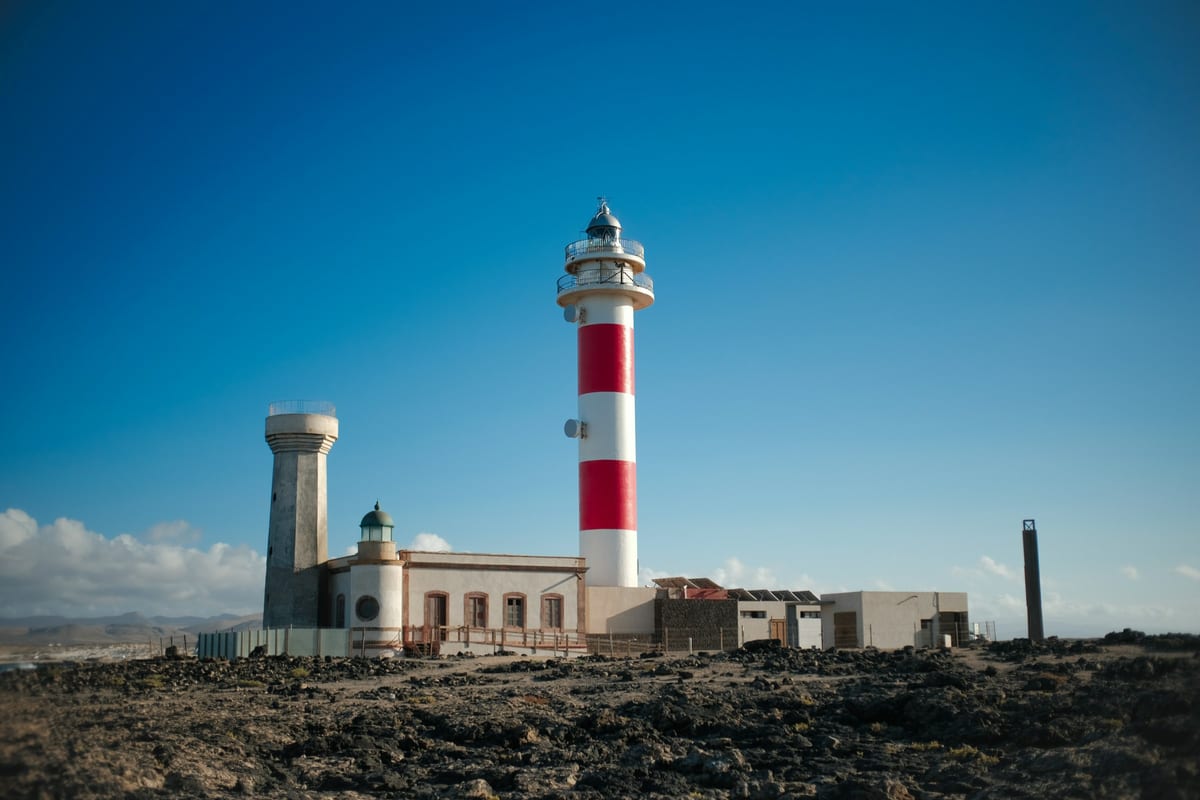 Červeno-biely maják El Tostón pri El Cotillo na skalnatom pobreží