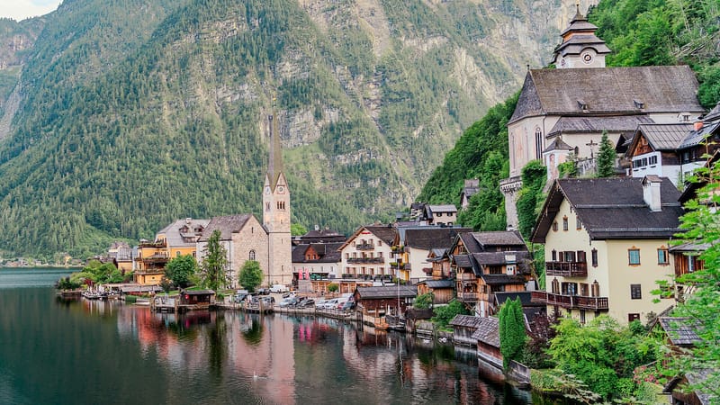 Hallstatt s kostolmi a domami na brehu Hallstattského jazera pod zalesnenými horami