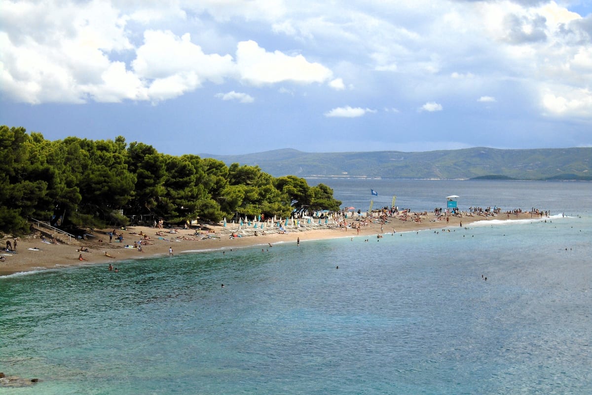Pláž Zlatni rat v Bole na ostrove Brač so zelenou vodou a borovicami
