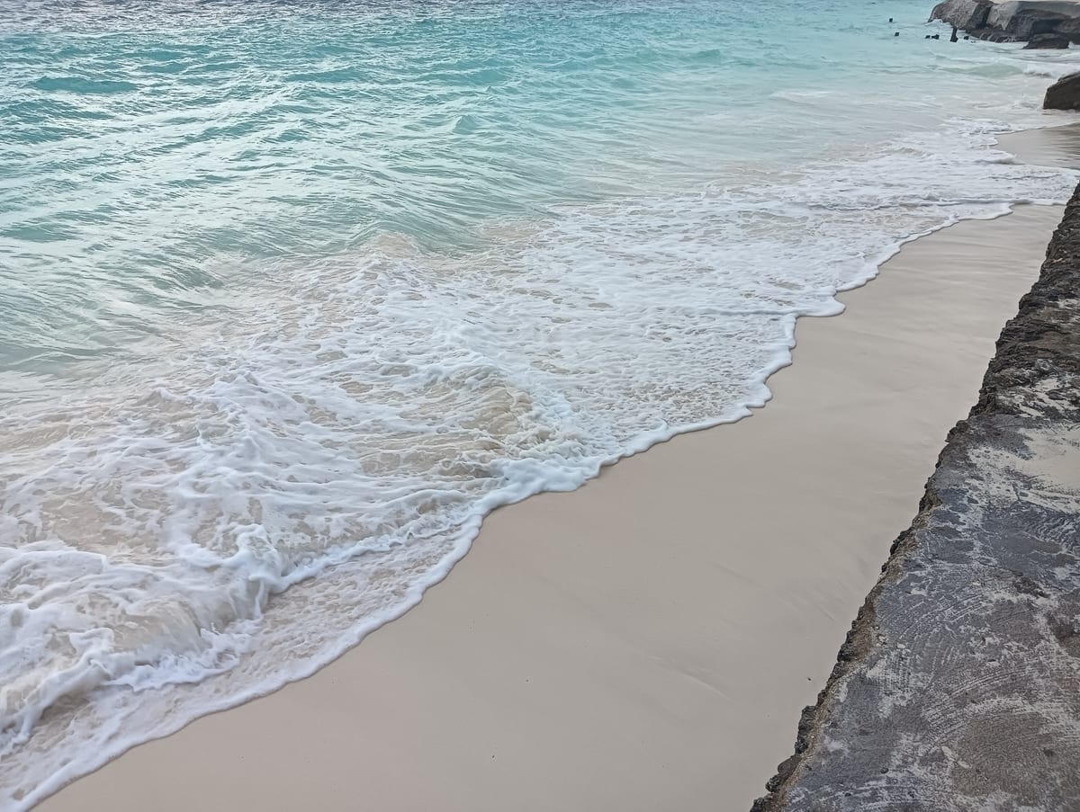 Pláž Nungwi na severe Zanzibaru s plytkým tyrkysovým morom a palmami pri hoteli.