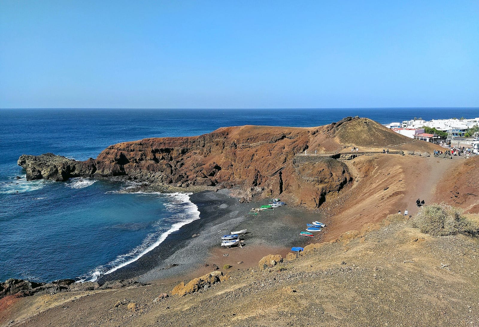 Čierna pláž s loďkami pod sopečným útesom pri dedine El Golfo na Lanzarote