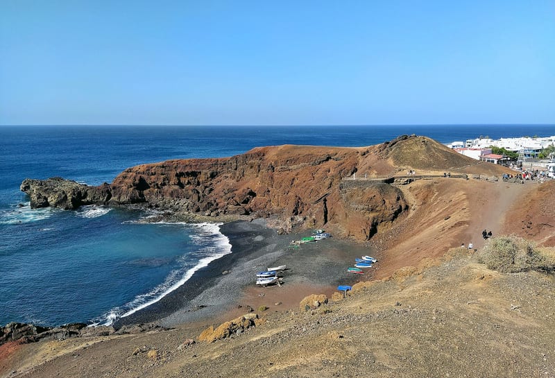 Čierna pláž s loďkami pod sopečným útesom pri dedine El Golfo na Lanzarote