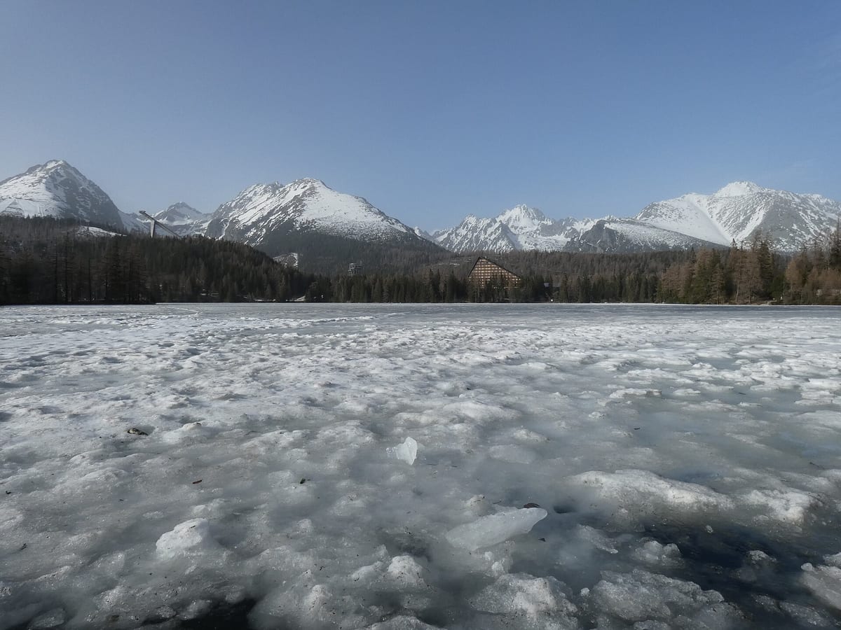Zamrznuté Štrbské pleso na jar so zasneženými štítmi Vysokých Tatier