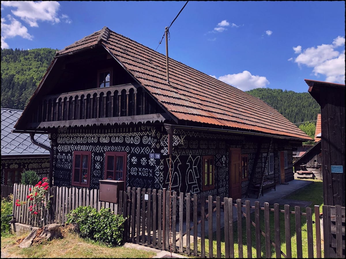 Tmavý drevený dom s bielymi ornamentmi v Čičmanoch