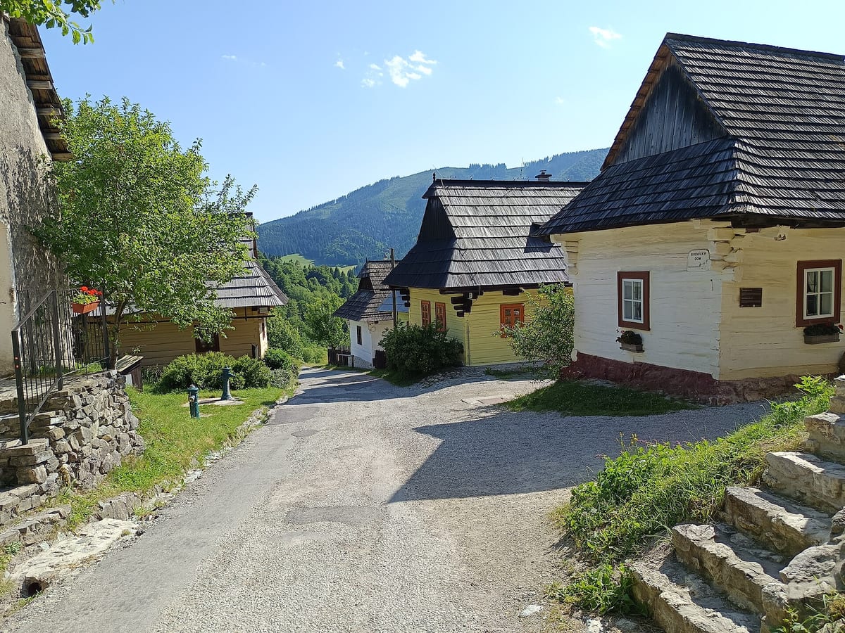 Zrubové domy so šindľovými strechami pozdĺž cesty vo Vlkolínci