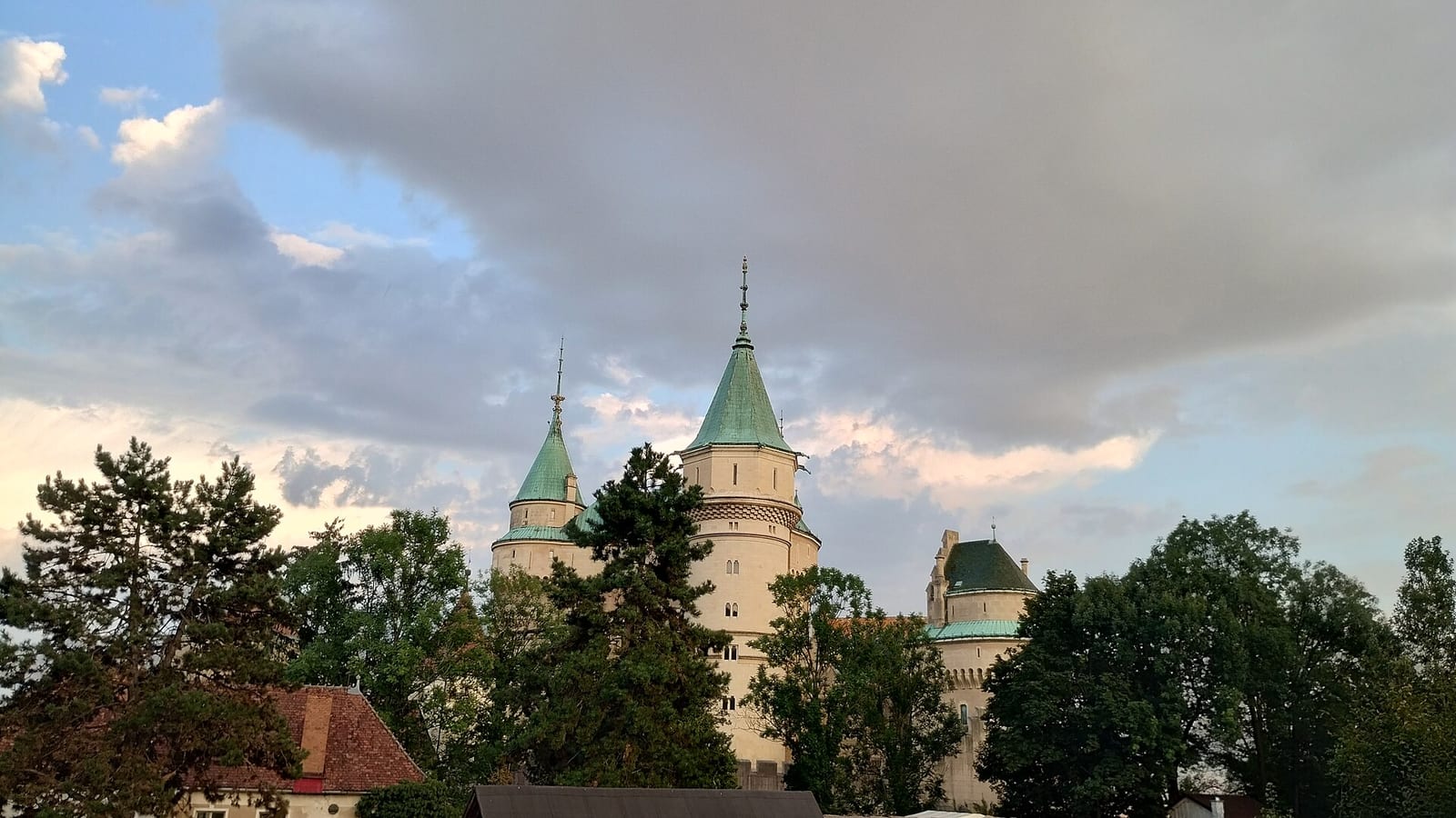 Bojnický zámok so zelenými strechami veží nad stromami zámockého parku