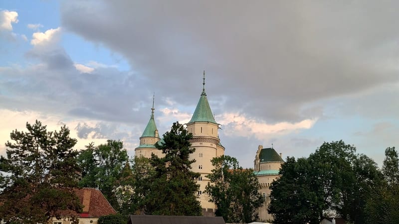 Bojnický zámok so zelenými strechami veží nad stromami zámockého parku