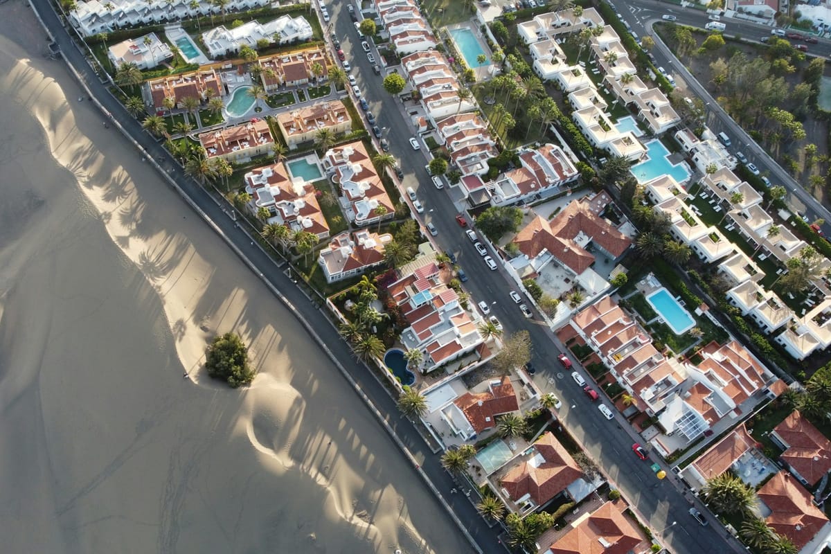 Letecký pohľad na duny Maspalomas, ktoré siahajú k hotelom s bazénmi na Gran Canarii