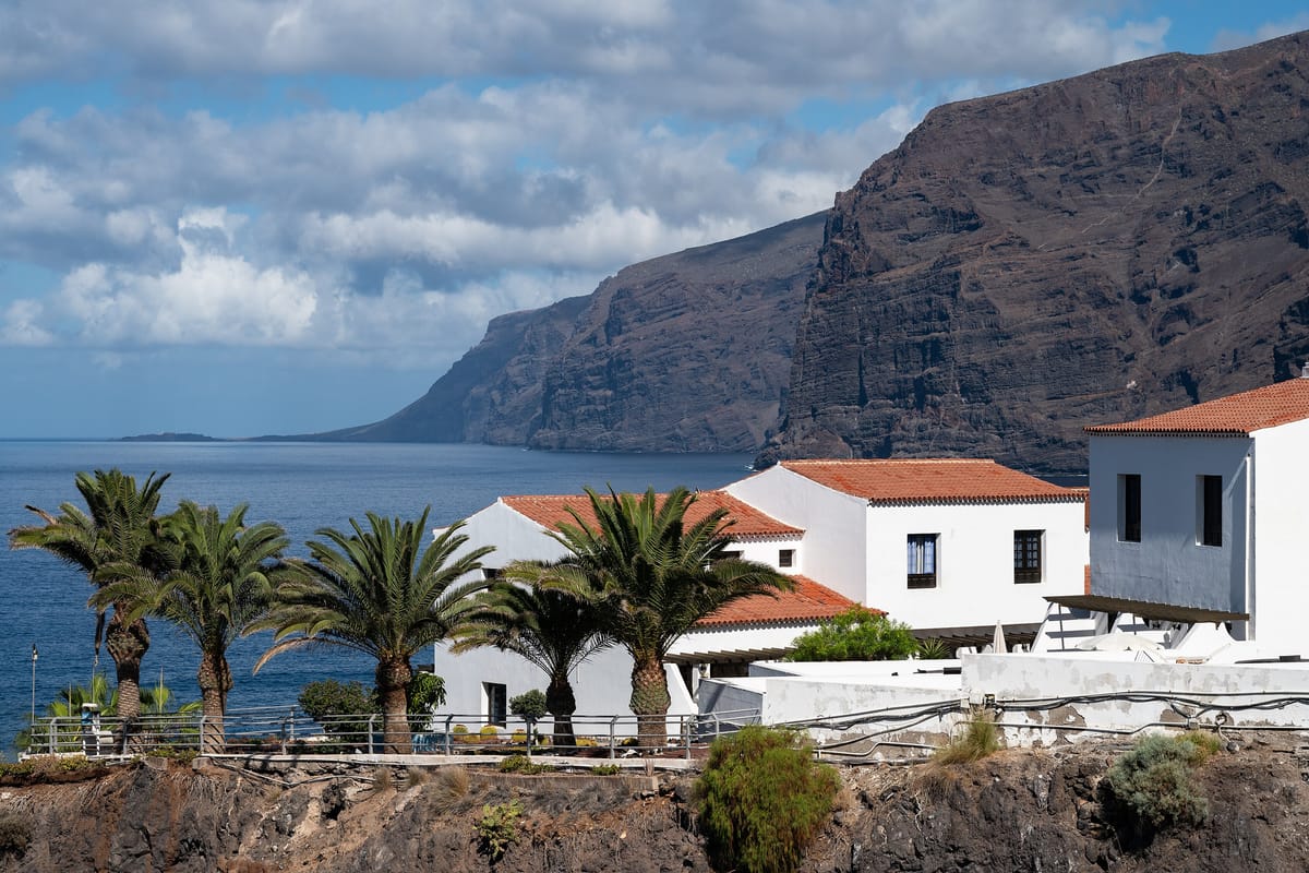 Útesy Los Gigantes nad morom a biele domy s palmami na západe Tenerife