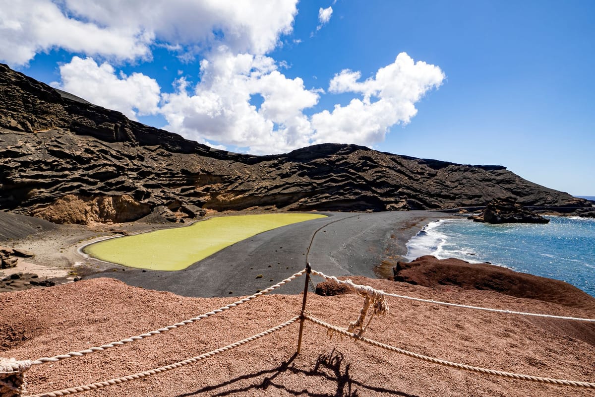 Zelená lagúna El Golfo pri čiernej pláži pod sopečnými skalami na Lanzarote