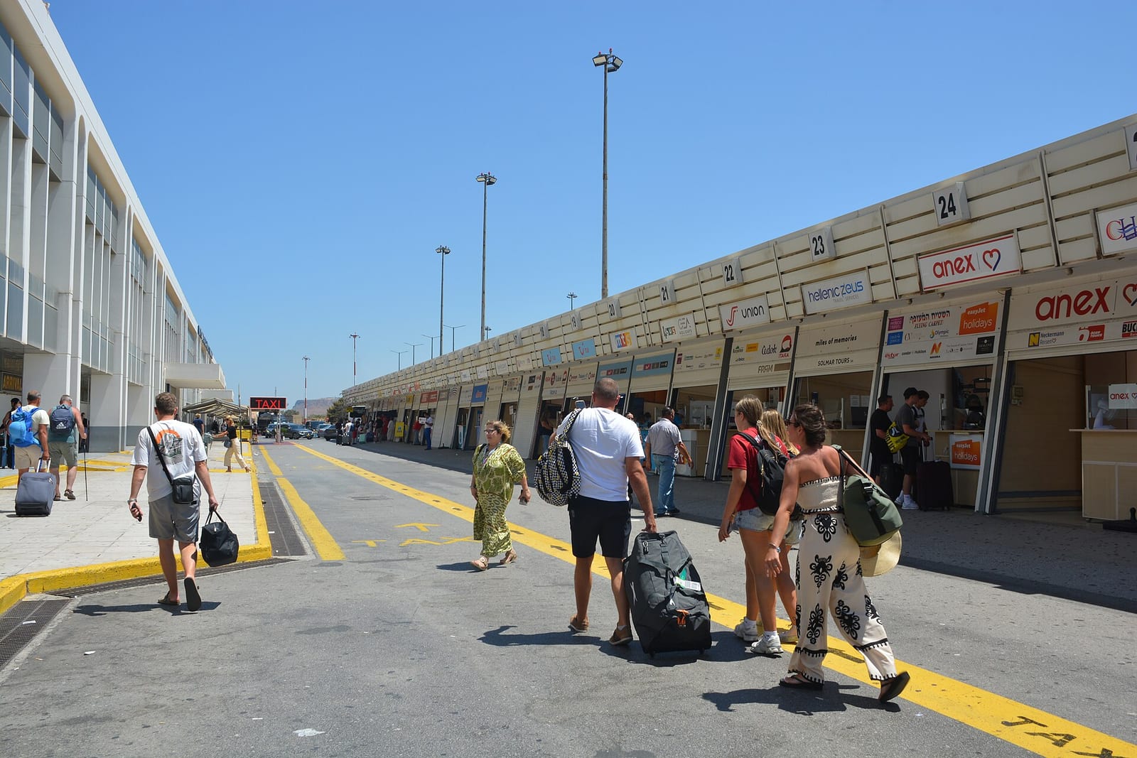 Cestujúci s kuframi pred odletovou halou letiska Heraklion Nikos Kazantzakis
