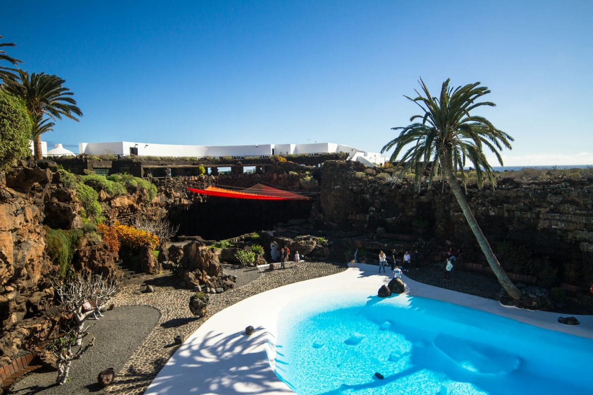 Biely bazén s modrou vodou a palmami v Jameos del Agua od Césara Manriqueho