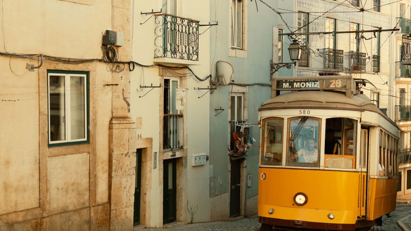 Žltá električka linky 28 s tabuľou Martim Moniz v úzkej ulici Lisabonu