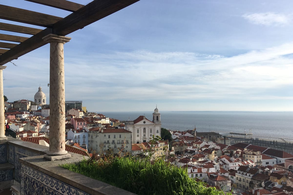 Vyhliadka so stĺpmi nad strechami Alfamy, kupolou Panteónu a riekou Tejo