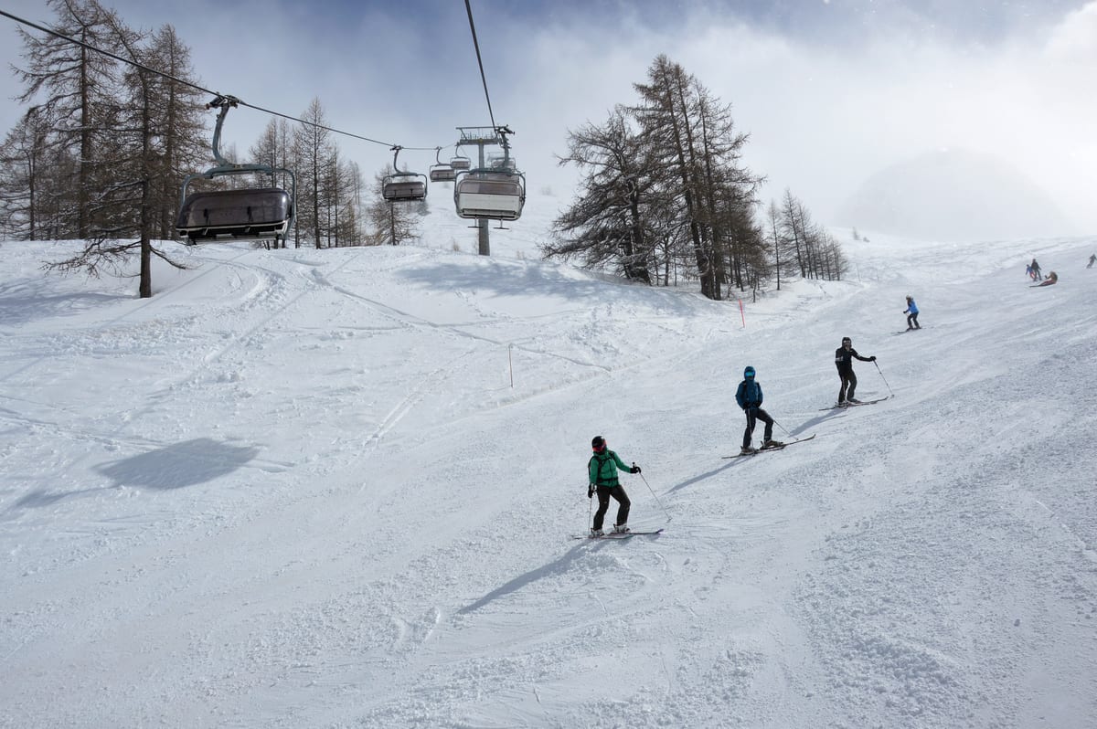 Lyžiari na zjazdovke pod sedačkovou lanovkou v La Thuile v Taliansku