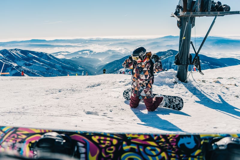 Snowboardistka si pripravuje výstroj na Chopku v Jasnej, v pozadí hrebene Nízkych Tatier