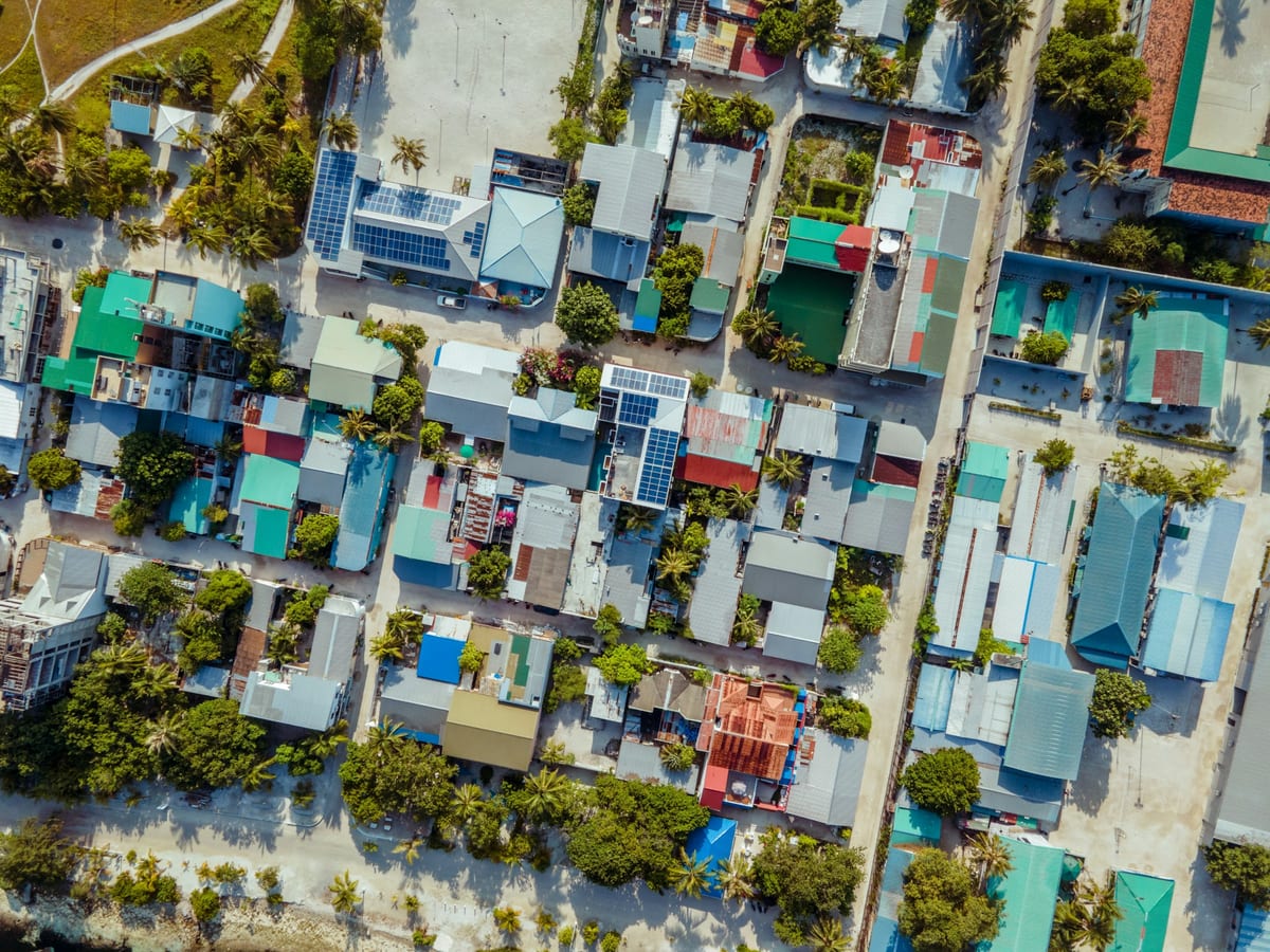 Letecký pohľad na strechy domov, ulice a palmy na miestnom ostrove Maafushi