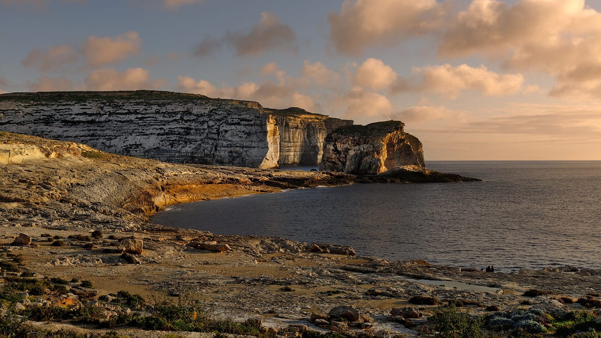 Vápencové útesy a skala Fungus Rock pri zálive Dwejra na ostrove Gozo pri západe slnka