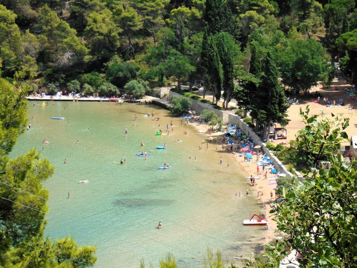 Piesočná pláž Lovrečina pri Postire na ostrove Brač, odfotená zhora cez borovice.