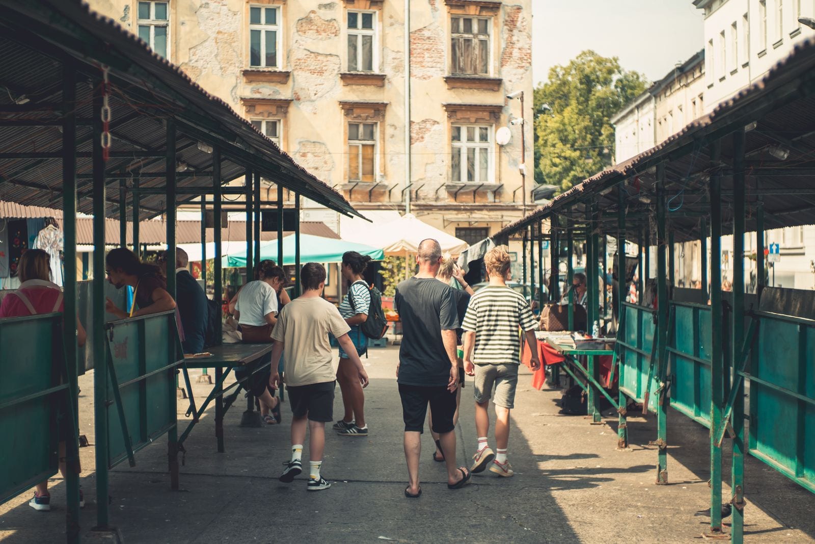 Ulička medzi krytými stánkami na trhu v Poľsku, ľudia idú pomedzi predajcov