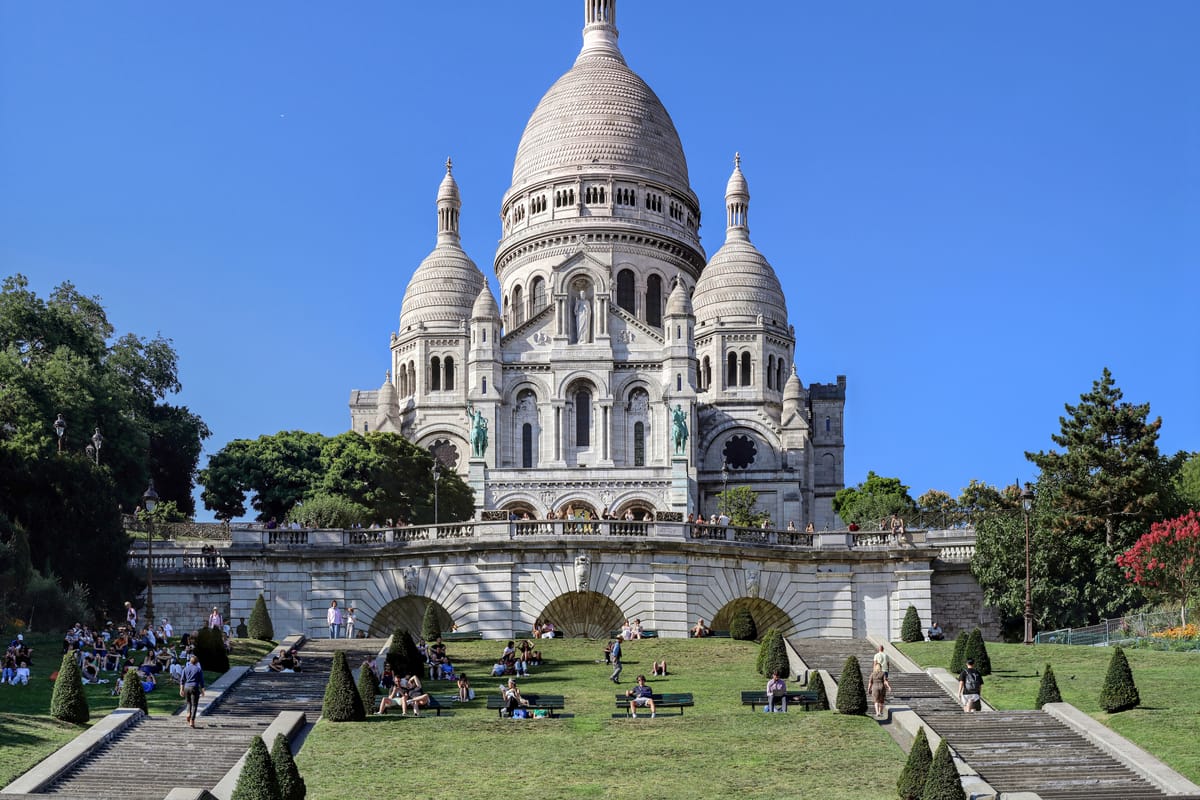 Bazilika Sacré-Cœur na Montmartri s trávnikom a schodmi pod ňou
