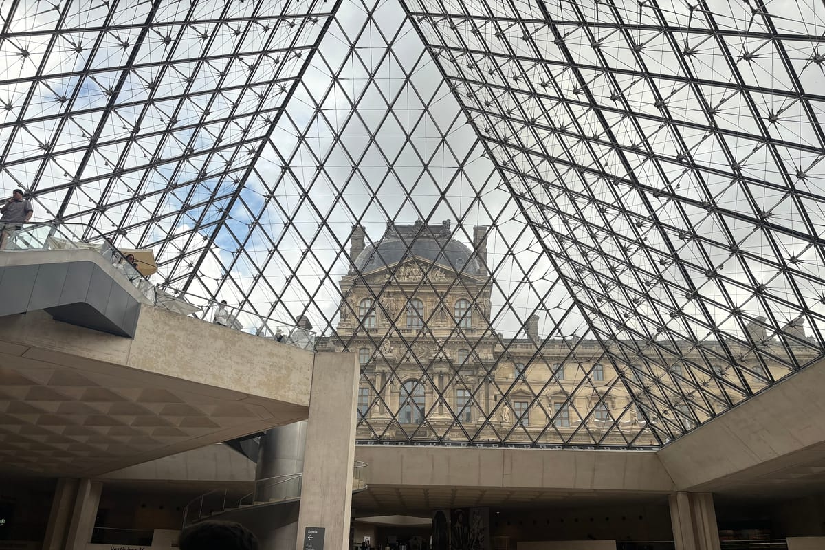 Vstupná hala pod sklenenou pyramídou Louvru s pohľadom na palác
