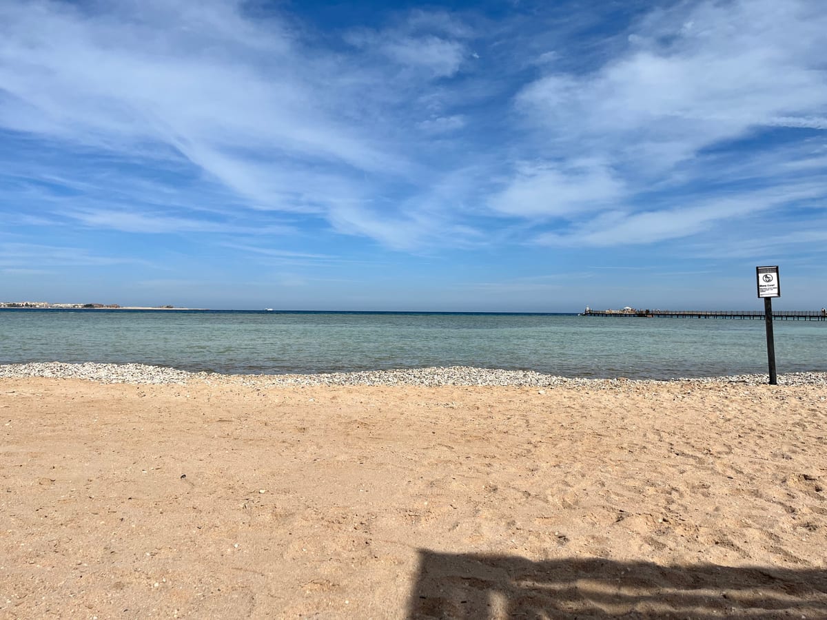 Piesočná pláž s tyrkysovým morom a modrou oblohou v Sahl Hasheesh