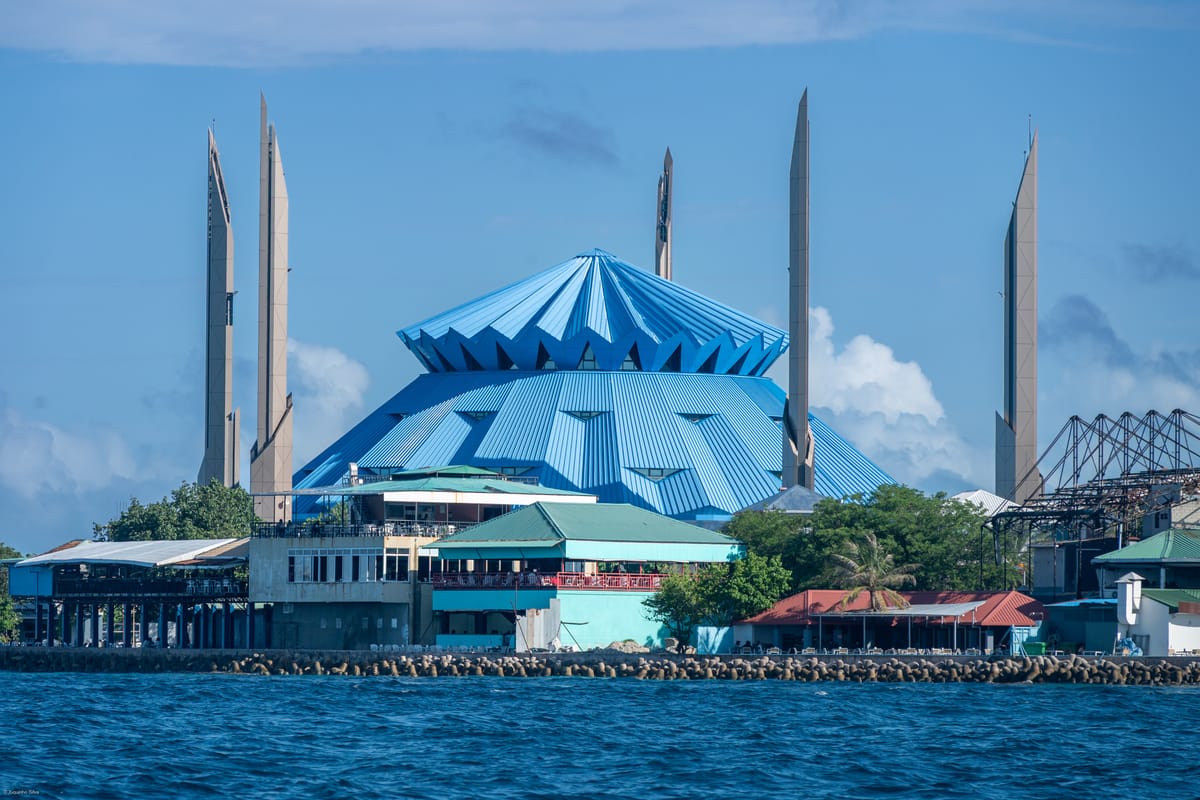 Nábrežie v Malé s modrou kupolou mešity a minaretmi nad tyrkysovou vodou