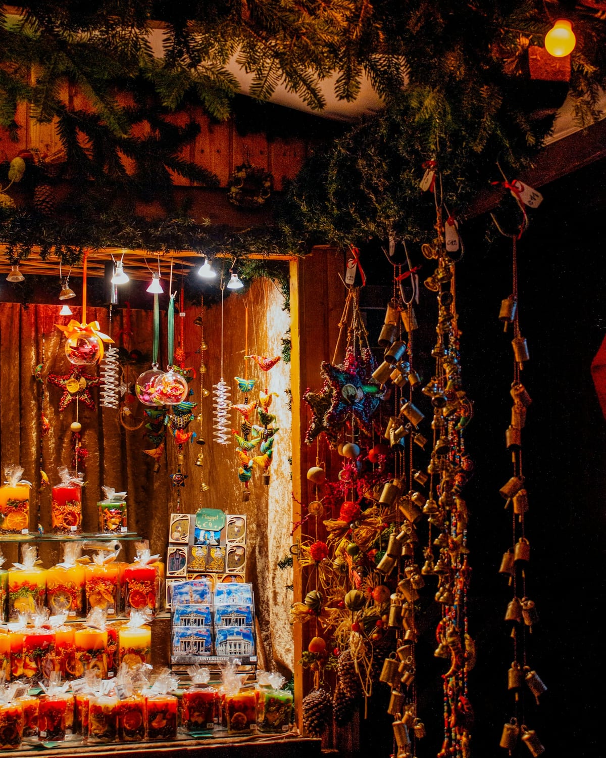 Drevený stánok so sviečkami a vianočnými ozdobami na adventnom trhu večer