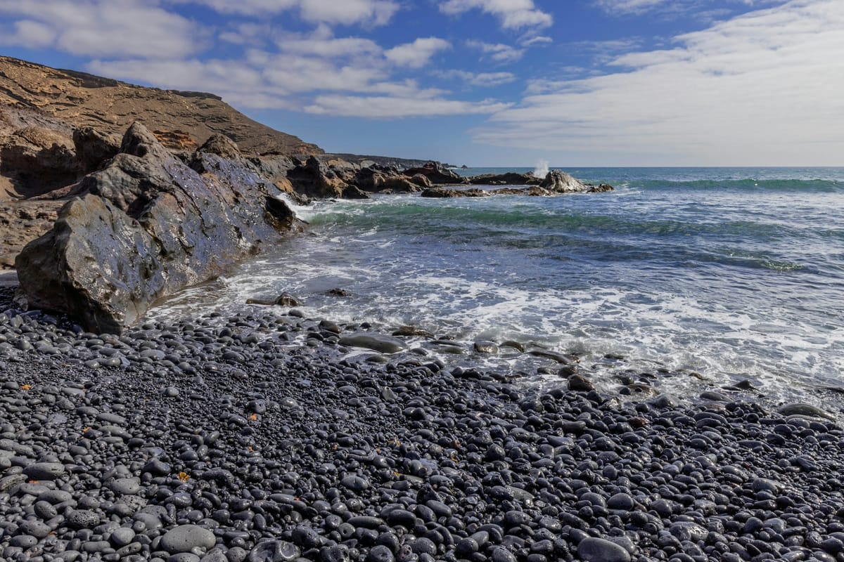 Kamenistá sopečná pláž na Lanzarote pod oblačnou oblohou v decembri