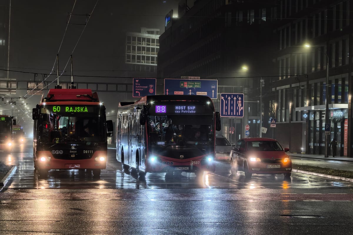 Mestské autobusy DPB liniek 60 a 88 na mokrej ulici v Bratislave v noci