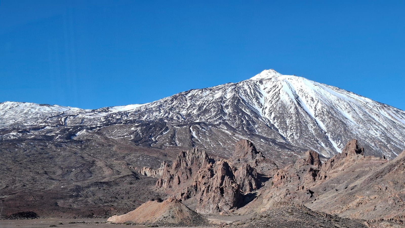 Zasnežený vrchol Teide nad skalami Roques de García v národnom parku v decembri 2025