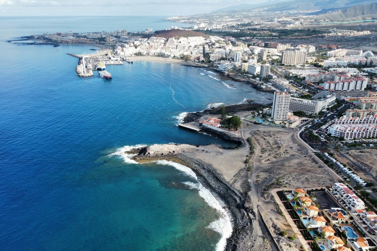 Prístav a pláže v Los Cristianos na juhu Tenerife z výšky, za nimi hotely a Playa de las Américas