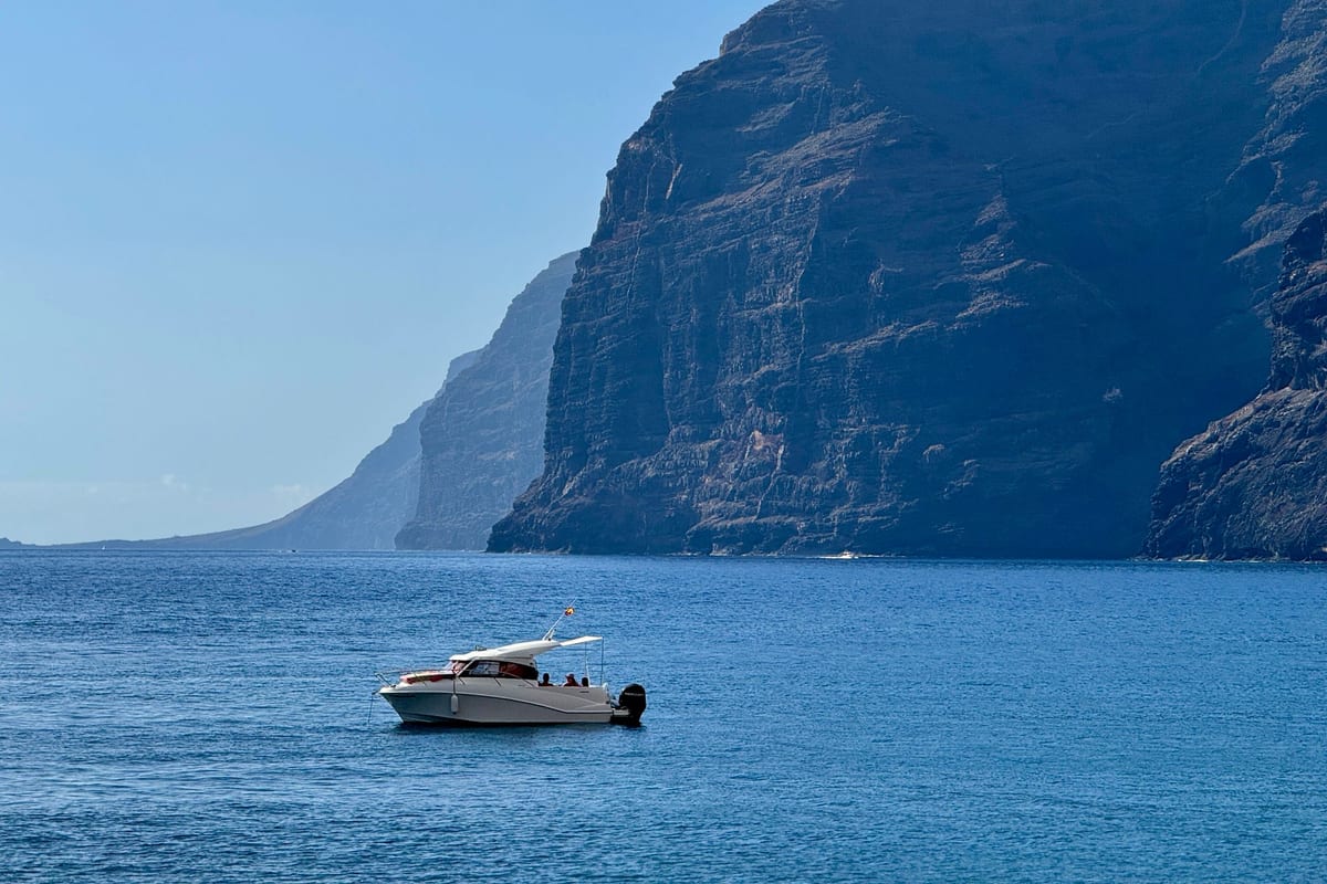 Motorový čln na pokojnom oceáne pod útesmi Los Gigantes na západnom pobreží Tenerife
